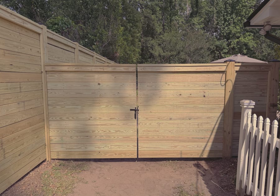 A tall horizontal board fence with a capped top rail and a matching double gate.